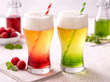 Helles Weißbier mit rotem Sirup im Glas auf hellem Holztisch