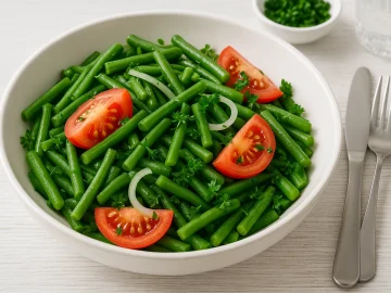 Bohnen-Tomaten-Salat mit grünen Bohnen, Tomaten, Zwiebeln und Petersilie in einer weißen Schüssel serviert