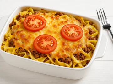 Hackfleisch-Nudel-Auflauf mit Tomaten, Zwiebeln und Käse überbacken in einer Auflaufform auf Holzhintergrund