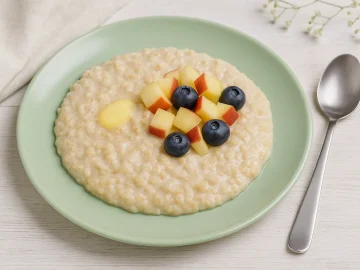 Haferflockenbrei mit frischem Obst auf einem hellgrünen Teller, serviert auf Holzhintergrund