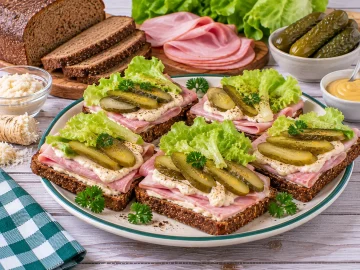 Schwarzbrotschnitten mit Schinken, Meerrettich und Gewürzgurken.