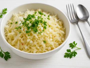 Sauerkohlsalat mit Apfelraspeln, Zwiebeln und frischer Petersilie in Schüssel auf weißem Holztisch