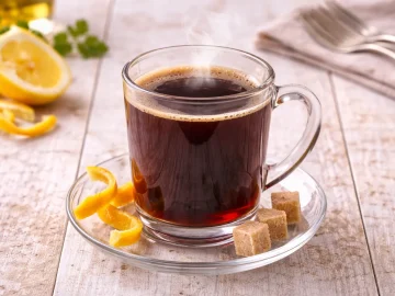 Spanischer Kaffee mit Rotwein und Weinbrand in Glasbecher auf hellem Holztisch