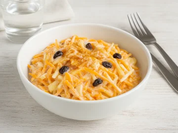 Süße Kürbisrohkost mit Kürbis, Äpfeln, Korinthen und Joghurt in einer weißen Schüssel serviert