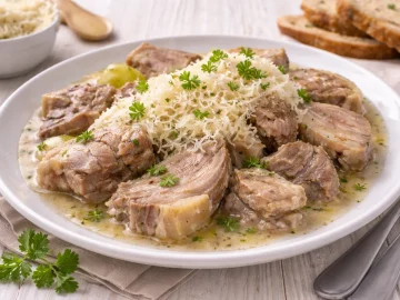 Gekochtes Schweinefleisch mit geriebenem Meerrettich auf weißem Teller auf hellem Holztisch