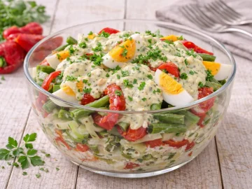 Ungarischer Eiersalat mit Bohnen, Ei und Paprika in Glasschüssel auf hellem Holztisch