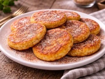 Goldbraune Kartoffelküchel mit Zucker und Zimt auf weißem Teller