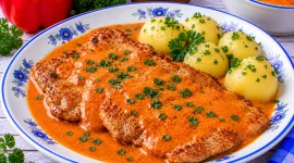 Gebratenes Schweineschnitzel mit cremiger roter Paprika-Sahne-Soße.