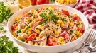 Hühnersalat mit Mais, Tomaten, Zwiebeln und Petersilie in cremigem Dressing in einer weißen Schüssel