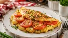 Goldbraunes Kartoffel-Tomaten-Omelett auf weißem Teller mit Schnittlauch und rustikalem Holztisch