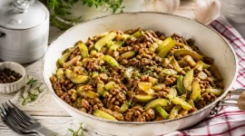 Schmorgurkenpfanne mit Hackfleisch in rustikaler Pfanne auf hellem Holztisch angerichtet