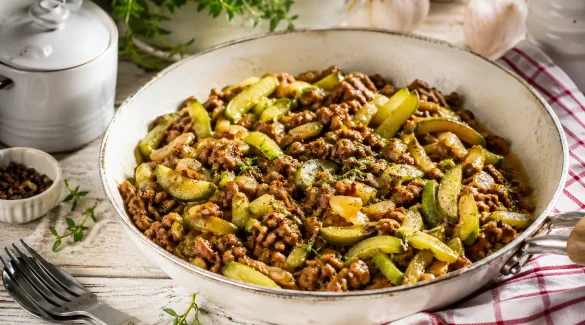 Schmorgurkenpfanne mit Hackfleisch in rustikaler Pfanne auf hellem Holztisch angerichtet