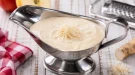 Apfel-Meerrettichsoße in Edelstahlsauciere auf weißem Holztisch angerichtet