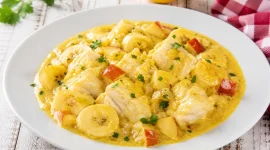 Kabeljauragout mit Curry, Apfel und Banane in cremiger Soße auf weißem Teller angerichtet