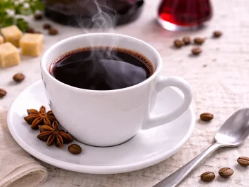 Heißes Getränk aus Kaffee, Rotwein und Wodka in weißer Tasse auf hellem Holzhintergrund