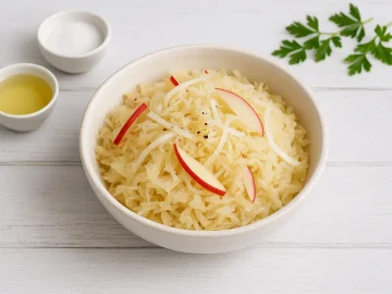 Sauerkrautsalat mit Apfel und Zwiebel in heller Schale auf weißem Holzhintergrund