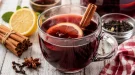 Ungarischer Punsch mit Zimt, Nelken und Zitrone in Tasse auf weißem Holztisch