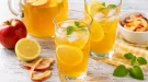 Erfrischende Apfeltee-Limonade mit Zitrone in modernen Gläsern auf rustikalem weißen Holztisch