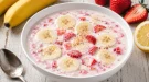 Bananenkaltschale mit Erdbeeren in weißer Schüssel auf hellem Holztisch