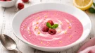 Himbeersuppe mit Quark in weißer Schüssel auf rustikalem Holztisch
