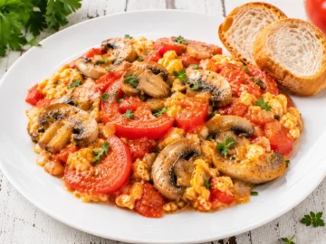 Pilze mit Tomaten und Ei auf modernem weißen Teller serviert