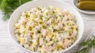 Schwedischer Fischsalat mit Ei und Gewürzgurke in moderner weißer Schüssel auf rustikalem weißen Holztisch