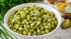 Salat aus sauren Gurken mit Zwiebeln und frischen Kräutern in weißer Schüssel