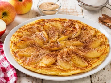Apfel-Eierkuchen mit Apfelscheiben und Zimtzucker auf weißem Teller