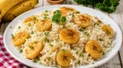 Bananenreis mit goldbraun gebratenen Bananenscheiben auf weißem Teller