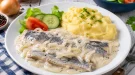 Bücklingsfilet in cremiger saurer Sahne mit Zwiebeln auf weißem Teller
