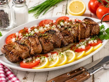 Gegrilltes Rinderfilet am Metallspieß mit Tomaten und Zitronenscheiben