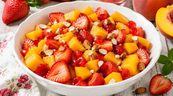 Pfirsichsalat mit Erdbeeren, Mandeln und Maraschinokirschen in weißer Schüssel
