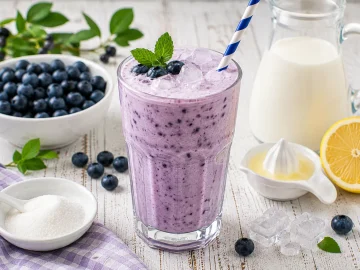 Cremiger Heidelbeer-Sahne-Drink mit frischen Heidelbeeren und Eiswürfeln in einem hohen Glas.