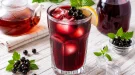 Kalter Johann in einem hohen Glas mit Eiswürfeln und frischen schwarzen Johannisbeeren.