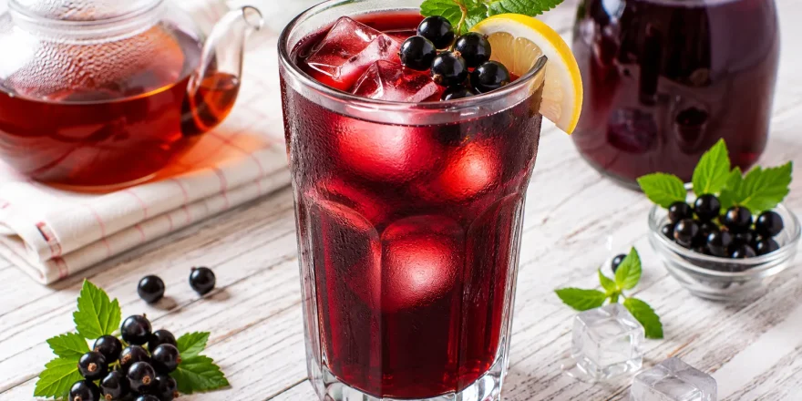 Kalter Johann in einem hohen Glas mit Eiswürfeln und frischen schwarzen Johannisbeeren.