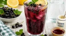 Prickelnder Vitaminsprudel aus Johannisbeer- und Zitronensaft in einem hohen Glas mit frischen Beeren.
