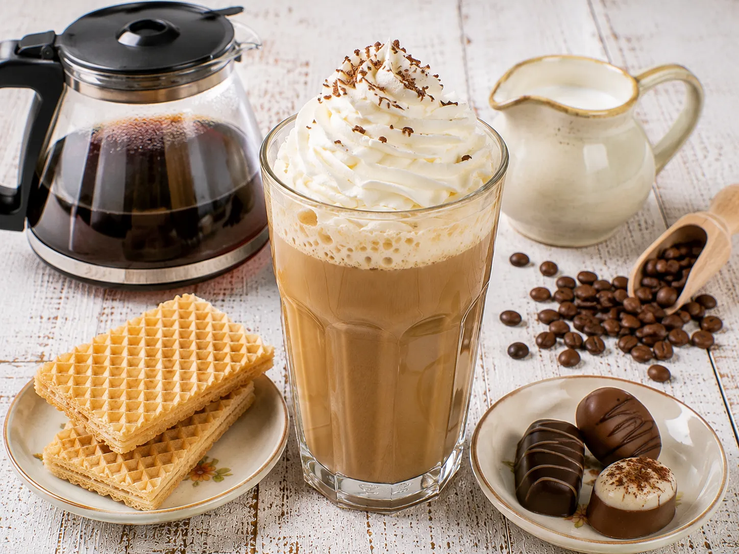 Eiskaffee mit Sahnehaube in einem hohen Glas und Waffeln.