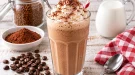 Cremiger Mokka-Milch-Shake mit Sahne und Kakaopulver in einem hohen Glas.