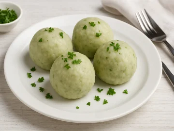 Traditionelle vogtländische grüne Klöße aus Kartoffeln auf weißem Teller mit frischen Kräutern
