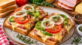 Überbackener Toast mit Kasseler, Käse, Tomaten und Paprika.