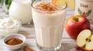 Cremige Zimtmilch mit Apfelscheiben in einem hohen Glas.