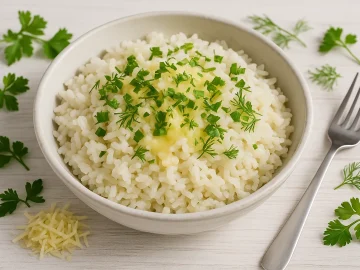 Käsereis mit geschmolzenem Käse und frischen Kräutern in weißer Schüssel, Holzhintergrund, modernes Besteck