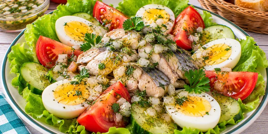 Rostocker Fischteller mit Fisch, Eierscheiben, Tomaten und grünem Salat.