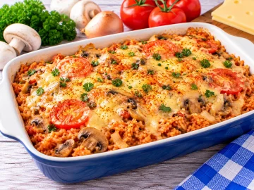 Italienischer Reistopf mit Champignons, Tomaten und geschmolzenem Käse.