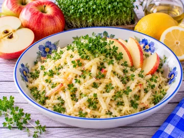 Frischer Apfelsalat mit geriebenen Äpfeln, Gartenkresse und Zitronenmarinade.