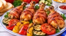Gegrillte Broilerkeulen mit Rauchspeck, Paprika, Tomaten und Gurken.