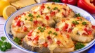 Überbackene Fischkoteletts mit Schinkenspeck, Camembert, Paprika und Schnittkäse.