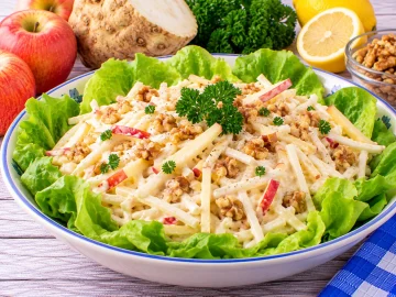 Würziger Apfelsalat mit Selleriestreifen, gehackten Nüssen und Mayonnaise.