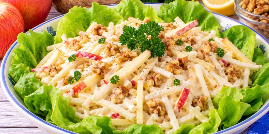 Würziger Apfelsalat mit Selleriestreifen, gehackten Nüssen und Mayonnaise.