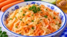 Sauerkrautsalat mit geraspelten Karotten und Honig in einer hellen Salatschüssel.